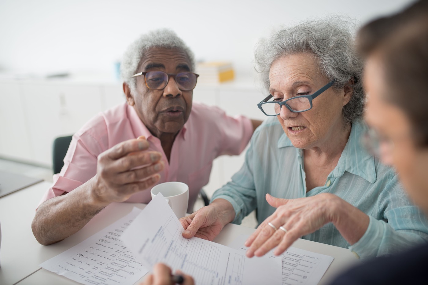 A man in his seventies and his adult daughter go through a printed checklist together at a table.